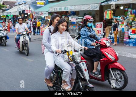 Hübsche vietnamesische Schülerinnen tragen traditionelle weiße AO dai Kleider fahren Roller ohne Sturzhelm, Da Nang, Vietnam Stockfoto