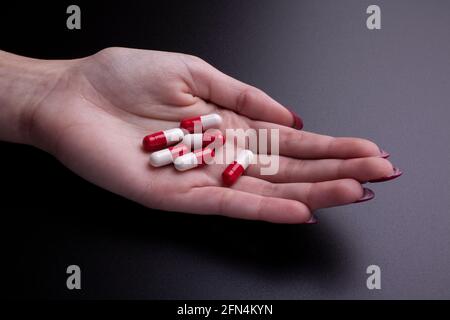 Frau mit einigen Drogenkapseln auf der Handfläche - Schwarzer Hintergrund Stockfoto
