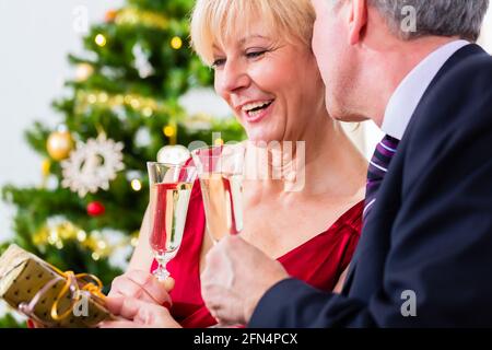 Ältere Mann und Frau feiern Heiligabend mit einem Glas Sekt Stockfoto