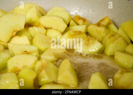 Scheiben von grünen Äpfeln karamellisieren in der Pfanne mit Zucker (Foto mit geringer Schärfentiefe) Stockfoto