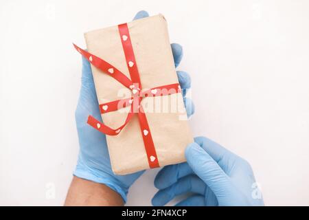 Männliche Hand in einem blauen medizinischen Handschuh gibt ein Geschenk. Stockfoto