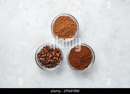 Drei Tassen mit verschiedenen Kaffeesorten auf grauem Hintergrund. Draufsicht, horizontal. Stockfoto