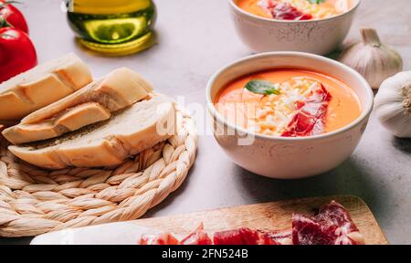 Salmorejo-Suppe in den Schüsseln mit Marmelade, Olivenöl und gekochtem Ei auf Marmortisch. Gazpacho Tomatensuppe. High-Angle-Ansicht Stockfoto