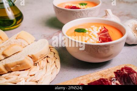 Salmorejo-Suppe in zwei Schüsseln mit Marmelade und gekochtem Ei auf einem Marmortisch. Traditionelles spanisches Gazpacho-Püree Stockfoto