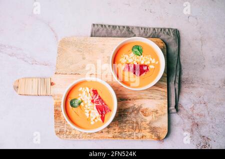 Tomatensuppe in zwei Schüsseln auf einem Holztisch. Salmorejo, kalte Suppe mit spanischen Gazpacho-Tomaten. Ansicht von oben oder flach liegend Stockfoto