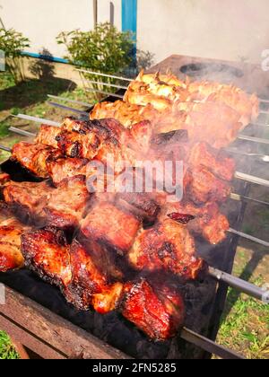 Marinierter Schaschlik, der auf einem Barbecue-Grill über Holzkohle zubereitet wird. Schaschlik oder Schischkebab in Europa beliebt. Stockfoto