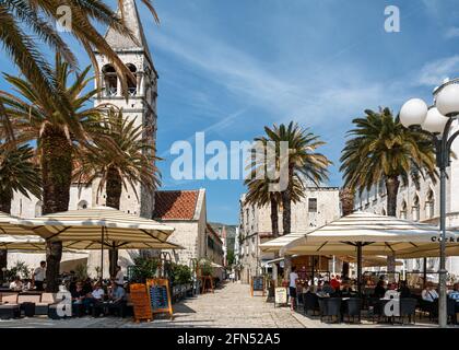 Café-Terrassen mit Touristen auf der Promenade in Trogir, Kroatien Stockfoto