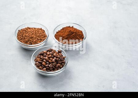 Drei Tassen mit verschiedenen Kaffeesorten auf grauem Hintergrund. Seitenansicht, Kopierbereich. Stockfoto