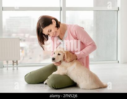 Schöne Frau streicheln schönen kleinen Hund in hellen Raum Stockfoto