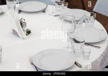 Hochzeit. Bankett. Tisch für Gäste, werden mit Besteck und Geschirr serviert und mit einer Tischdecke bedeckt. Schön gedeckte Tafel mit Gläsern und Tellern Stockfoto