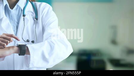 Zusammensetzung der Mittelsektion der Ärztin im Laborkittel mit Smartwatch über Krankenhaus ohne Fokus Stockfoto