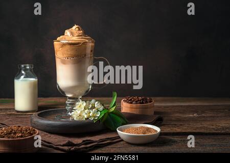 Kaffee-Dessert mit Milch und Eis auf braunem Hintergrund. Dalgona Kaffee. Stockfoto