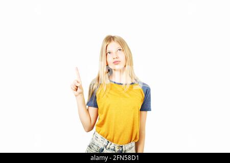 Junge schöne Teenager-Mädchen mit blonden Haaren trägt gelbe Baseballshirt mit blauen Ärmeln, zeigt auf Kopie Raum mit ihrem Finger. Hübsches Mädchen, SM Stockfoto