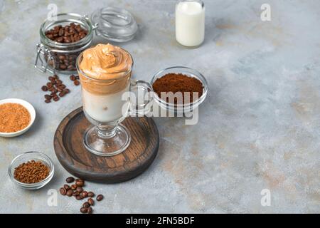 Erfrischender Dalgona-Kaffee mit Milch, Schaum und Eis auf grauem Hintergrund. Koreanischer Kaffeedrink. Stockfoto