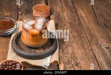 Sommergetränk, Eiskaffee mit Milch auf Holzboden mit Kaffeebohnen. Seitenansicht, Kopierbereich. Stockfoto
