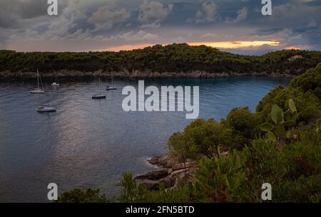 Panoramablick auf Segelboote auf dem Wasser auf dramatische Sonnenuntergänge Blick auf leeren Strand von Fetovaia, Insel Elba, Toskana, Italien Stockfoto