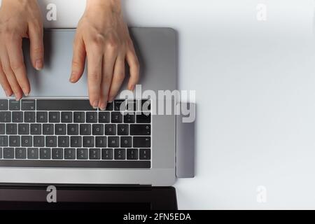 Nahaufnahme der Hände, die auf einer Laptop-Tastatur tippen. Minimalistisch Stockfoto