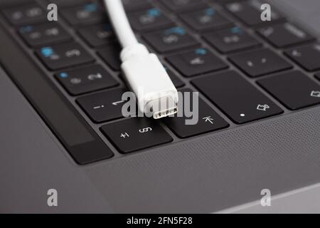 Nahaufnahme eines weißen Typ-C-Kabels, das auf einer Laptop-Tastatur liegt. Stockfoto