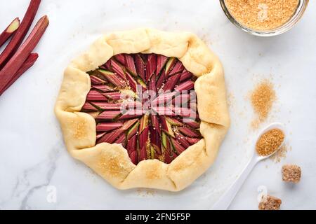 Galette mit frischem Rhabarber Prozess der Zubereitung und Zutaten Mehl, Wasser, Butter, Zucker und Rhabarber zum Backen auf weißem Marmor Hintergrund. Chris Stockfoto