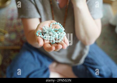 Eine Frau, die eine halskette mit mala-Yoga-Gebetsperlen in der Hand hält. Stockfoto