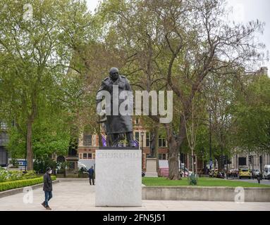 Fußgänger mit Gesichtsmast läuft vor der Statue von Winston Churchill auf dem Parliament Square, London, 14. Mai 2021 Stockfoto