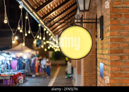 Der Circle Yellow Lightbox hat an der Wand vor dem Backsteinpfosten in einer Tungsten Umgebung Vintage Shopping Community Mall gehängt. Stockfoto