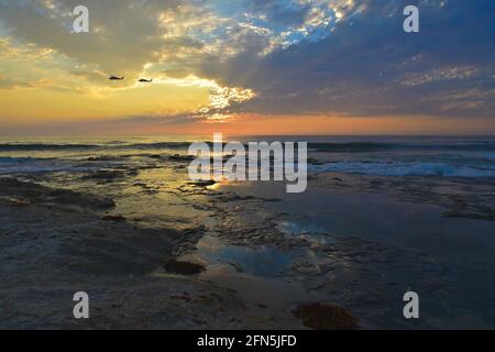 Die malerische Sonnenuntergangslandschaft mit zwei Hubschraubern, die über den La Jolla Tide Pools in San Diego, Südkalifornien, USA, fliegen. Stockfoto