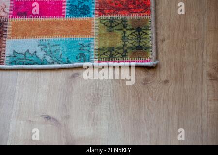 Farbenfroher Teppich auf Parkettboden. Draufsicht Stockfoto