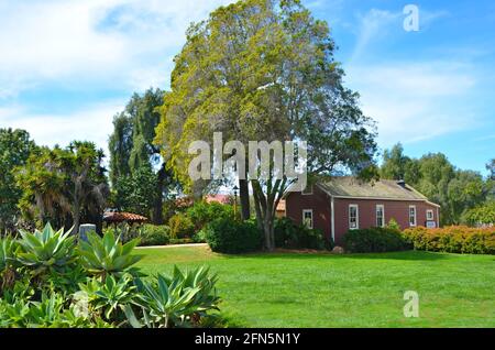 Malerischer Blick auf das Mason Street School House, ein Einzimmer-Gebäude mit rotem Holzrahmen und Schindeldach in den Old Town State Historic Park-Gärten in San Diego. Stockfoto