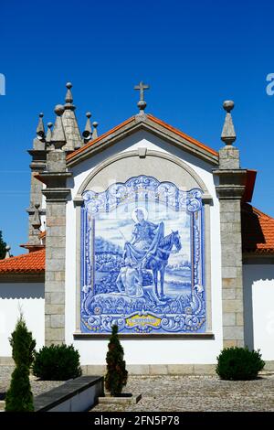 Keramikfliesen / Azulejos mit Bild von Sao Martinho an der Rückwand der Kirche San Martinho, Dorf Freixieiro de Soutelo, Provinz Minho, Portugal Stockfoto