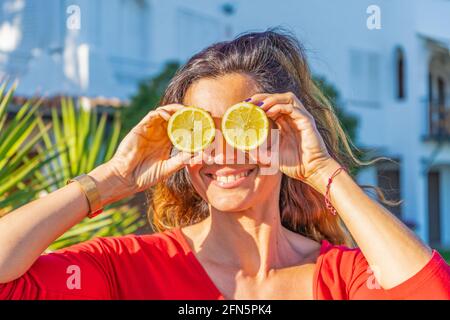 Glückliche Frau hält Zitronen vor den Augen Outdoor.Healthy Food Lifestyle, bunte Früchte Comic-Konzept. Stockfoto