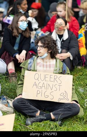 Protestierende, die mit Plakat auf Gras sitzt, während eines Protestes gegen das neue Polizeigesetz, London, 1. Mai 2021 Stockfoto