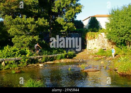 Mann radelt über die alte Steinbrücke über den Fluss Ancora in Porto Covo, in der Nähe von Vila Praia de Ancora, Provinz Minho, Nordportugal Stockfoto