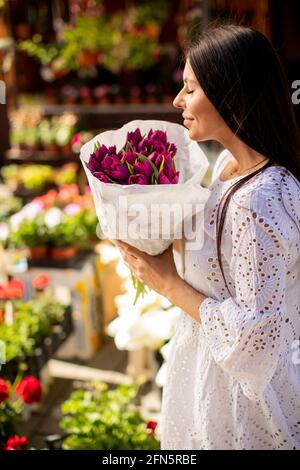 Hübsche junge Frau, die Blumen auf dem Blumenmarkt kauft Stockfoto