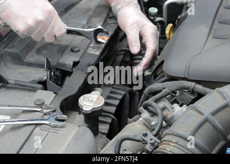 Die Hände eines Mechanikers fixieren einen Automotor Stockfoto