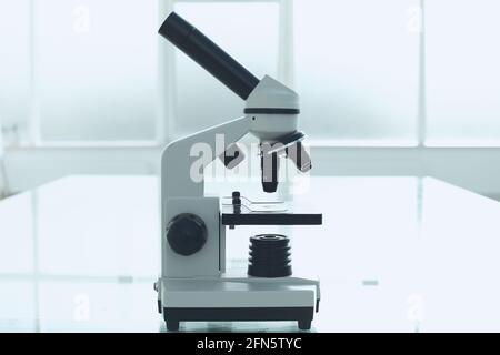 Mikroskop auf einem Glastisch in einem hellen Raum. Laborkonzept für medizinische Forschung Stockfoto