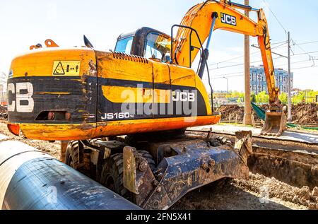 Samara, Russland - 6. Mai 2021: Baggerarbeiten am Straßenbau. Bagger gräbt einen Graben. Reparatur und Ersatz von unterirdischer Kommunikation Stockfoto