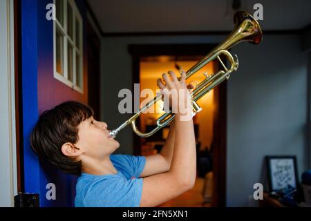 Ein Junge steht in einer bunten offenen Tür und spielt eine Trompete Stockfoto