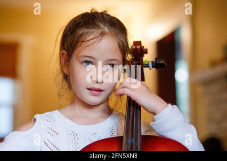 Nahaufnahme von fokussierten niedlichen Mädchen üben Cello zu Hause, Stockfoto