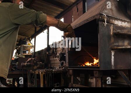 Schmied schürt in seiner Werkstatt ein Schmiedefeuer. Stockfoto