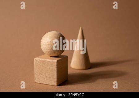 Holzspielzeug-Kindersorter mit kleinen Holzdetails in Form von geometrischen Formen Rechteck, Quadrat, Dreieck auf braunem Hintergrund, Figurenkonzept mit dunklen Schatten Stockfoto