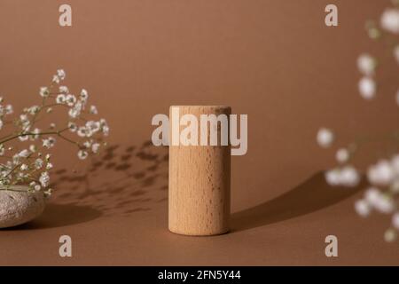 Hölzerne Zylinder und Blumen der braune pastellfarbene Hintergrund.gut wie Form geometrische Podien für die Darstellung von Produkten. Stockfoto