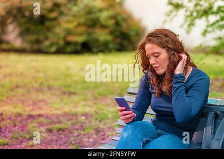 Rothaarige junge europäische Frau am Telefon im Freien Stockfoto