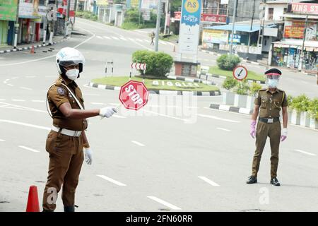 Colombo, Sri Lanka. Mai 2021. Ein Polizist hält Fahrzeuge an, um in Colombo, Sri Lanka, am 14. Mai 2021 zu checken. Die srilankischen Behörden haben am Mittwoch erklärt, dass strenge Reisebeschränkungen für die gesamte Insel eingeführt werden, um zu verhindern, dass sich die COVID-19-Pandemie im asiatischen Land weiter ausbreitet. Die landesweiten Reisebeschränkungen traten vom 13. Bis 31. Mai in Kraft. Quelle: Ajith Perera/Xinhua/Alamy Live News Stockfoto