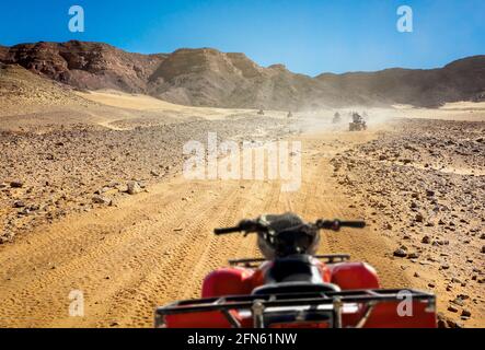 Safari-Tour mit Gruppe von Menschen auf Quad-Bikes, aktive Freizeit in Ägypten Resorts. Extreme Fahrten auf Quads in Steinwüsten. Stockfoto