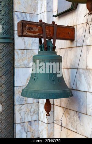 Die Kirchenglocke hängt an einem Balken, der aus der Wand ragt. Stockfoto