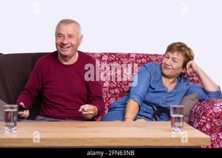 Porträt eines älteren Ehepaares, das in der Liebe zum Posen von Fotoshootings auf der Couch in modernen Studio-Apartments sitzt. Konzept der Aufnahme von glücklichen Momenten Stockfoto