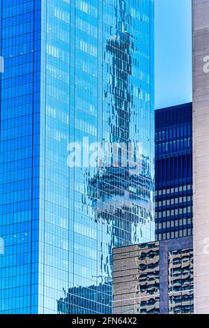 Ungewöhnlicher Winkel des CN Tower in der Innenstadt von Toronto, Kanada. Das Wahrzeichen spiegelt sich im Glas eines neuen Wolkenkratzers wider Stockfoto