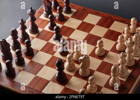 Klassisches hölzernes Turnierschach auf schwarzem Hintergrund. Schachbrett mit Stücken. Die Anordnung der Stücke stammt aus einer Öffnung, die als Queen's Gamb bekannt ist Stockfoto