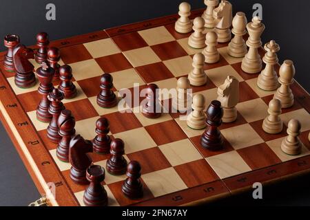 Klassisches hölzernes Turnierschach auf schwarzem Hintergrund. Schachbrett mit Stücken. Die Anordnung der Stücke stammt aus einer Öffnung, die als Queen's Gamb bekannt ist Stockfoto